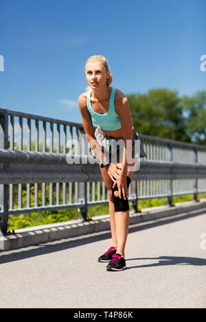 Fitness, sport, exercice et mode de vie sain concept - jeune femme avec renfort de support de genou sur l'extérieur de la jambe Banque D'Images