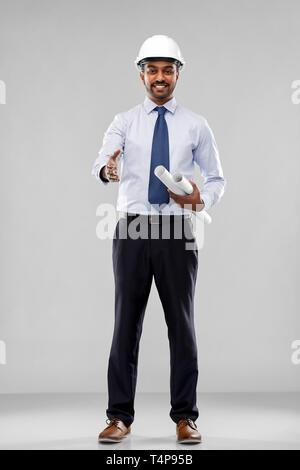 L'architecture, de la construction et du bâtiment - architecte indien souriant ou businessman in casque avec les bleus s'étendant hand out for handshake Banque D'Images