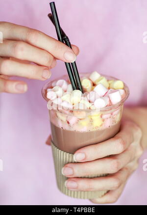 Le cacao de guimauve dans un gobelet jetable avec deux tubes dans les mains d'une femme Banque D'Images