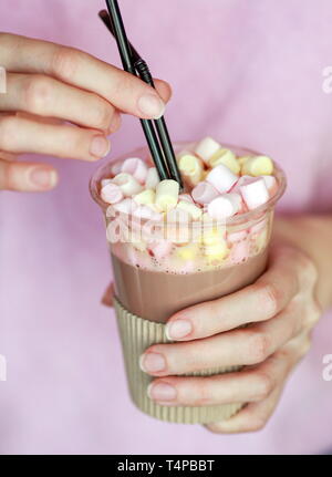 Le cacao de guimauve dans un gobelet jetable avec deux tubes dans les mains d'une femme Banque D'Images