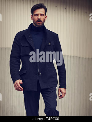 Barbe de mode style business modèle beau mâle en vêtements de style veste et pantalon bleu sur mur à l'extérieur de la rue arrière-plan. Ton Gros plan Banque D'Images