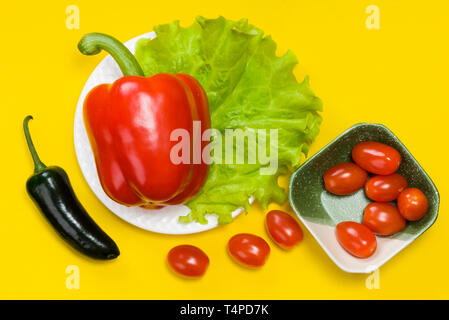 Still Life de piment jalapeno, le poivron, tomate cerise, de laitue sur fond jaune Banque D'Images