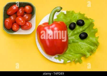 Still Life de poivron, la tomate cerise, la laitue et les olives sur fond jaune Banque D'Images