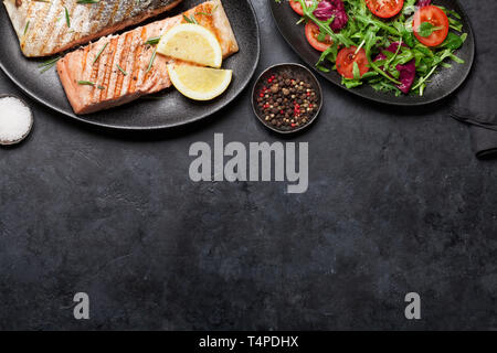 Filet de poisson Saumon grillé avec du sel, poivre et romarin. Avec la plaque de feuilles de salade. Sur table en pierre. Vue supérieure de la télévision. Avec l'exemplaire de l'espace pour votre tex Banque D'Images