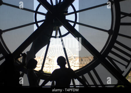 Trois touristes en silhouette tandis qu'ils admirent la vue sur la grande roue de la fenêtre derrière l'horloge énorme du musée d'Orsay à Paris France. Banque D'Images