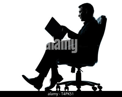 Un caucasian business man sitting in armchair lecture livre ancien en pleine longueur silhouette studio isolé sur fond blanc Banque D'Images