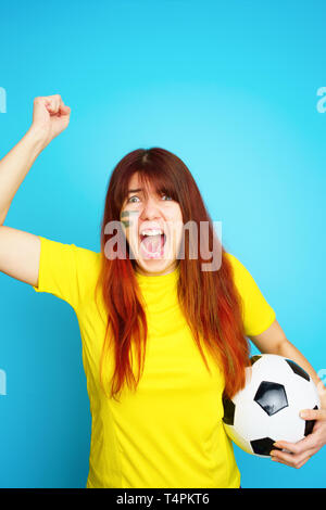 Femme est socccer en fan t-shirt jaune avec ballon de soccer Banque D'Images