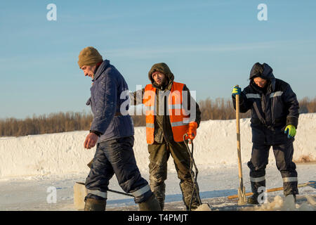 Les installateurs sur la glace de la rivière avec des pelles dans leurs mains à la construction de trous de glace Banque D'Images