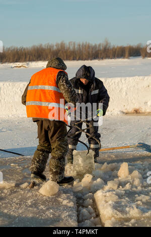 Tirez le bloc de glace travailleurs hors du trou avec des pinces en acier Banque D'Images