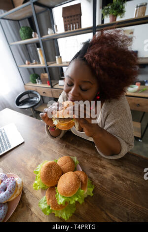 La jouissance de la vie. Ravie brunette gardant les yeux fermés tout en maintenant les deux mains en hamburger Banque D'Images