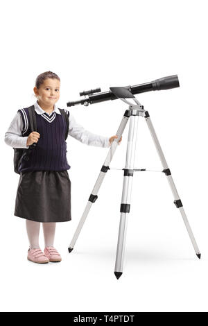 Portrait d'une petite fille dans un uniforme scolaire avec un télescope isolé sur fond blanc Banque D'Images