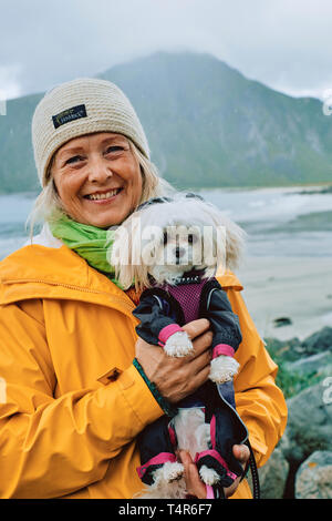 Le portrait d'une femme scandinave et son chien portant une veste imperméable dans le temps humide paysage de Norvège Banque D'Images