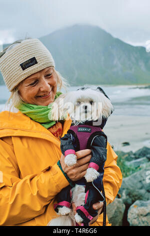 Le portrait d'une femme scandinave et son chien vêtu d'un imperméable étanche dans le temps humide paysage de Norvège Banque D'Images