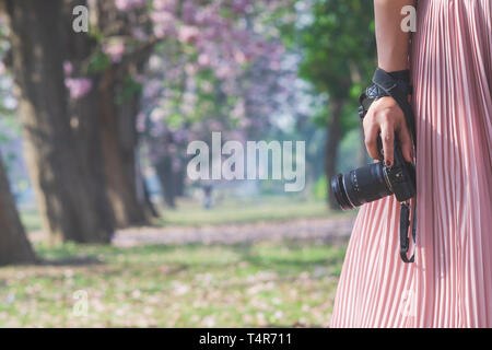 Close-up shot of woman holding camera. Jeune photographe hipster la préparation de l'appareil photo prise de vue dans l'air extérieur nature paysage . Banque D'Images