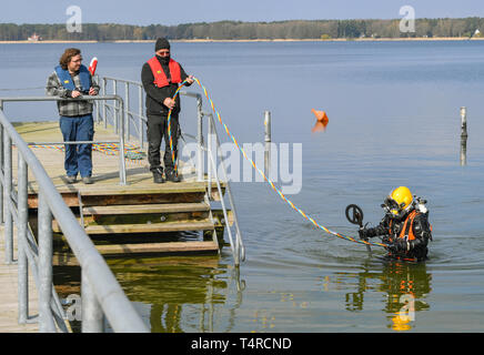 Wandlitz, Allemagne. 10 avr, 2019. Michael Padel (r), plongeur professionnel, il est équipé d'un détecteur de métaux à partir de l'eau du lac Wandlitz. Sur la jetée sont Eduard Hofmann (l), plongée assistant et Lutz Seelow, signaleur. La saison de baignade dans le lido à Wandlitzsee commence plus tard cette année. (À "trandbad Wandlitz reporte le début de la saison à cause d'armes à sous-munitions recherche') Credit : Patrick Pleul/ZB/dpa/Alamy Live News Banque D'Images