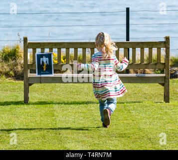 Château de Tantallon, Berwick Nord, Lothian oriental, Écosse, Royaume-Uni,19th avril 2019.Météo au Royaume-Uni : environnement historique le château écossais de 14th siècles organise un événement familial avec un sentier Eggslorer de Pâques pour que les enfants puissent chasser des indices sous le soleil du Vendredi Saint avec une vue sur le Firth of Forth.Une petite fille court pour trouver un des indices sur un banc au sommet de la falaise Banque D'Images