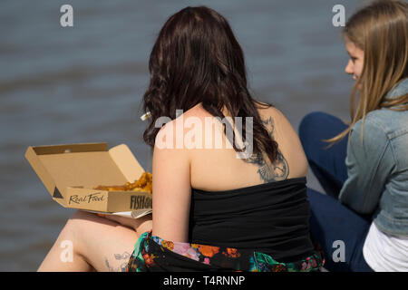 Femme mangeant du poisson et des chips à Blackpool, dans le Lancashire. 19 avril 2019. Météo britannique. L'été sizzler prévisions comme temps chaud prévu sur la côte de Fylde. Le soleil commence à la journée avec des températures qui devraient atteindre 20 c + dans le nord-ouest au début des vacances de Pâques du printemps. On peut s'attendre à ce que de la chaleur soit générée ce week-end, l'Angleterre et le Pays de Galles voyant le meilleur du soleil. Les météorologues du bureau de met disent que la chaleur stupéfiante d'avril sera encouragée par un soleil glorieux. Banque D'Images