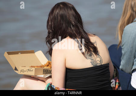 Femme mangeant du poisson et des chips à Blackpool, dans le Lancashire. 19 avril 2019. Météo britannique. L'été sizzler prévisions comme temps chaud prévu sur la côte de Fylde. Le soleil commence à la journée avec des températures qui devraient atteindre 20 c + dans le nord-ouest au début des vacances de Pâques du printemps. On peut s'attendre à ce que de la chaleur soit générée ce week-end, l'Angleterre et le Pays de Galles voyant le meilleur du soleil. Les météorologues du bureau de met disent que la chaleur stupéfiante d'avril sera encouragée par un soleil glorieux. Banque D'Images