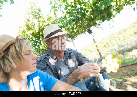 Man partager son expérience avec les gars dans le vignoble. Les gens les relations et la communication concept. L'homme en chapeau de paille vigneron parlant avec garçon. T Banque D'Images