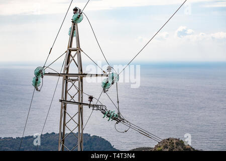 Pylon avec insulatros et lignes, fils, mer Adriatique en arrière-plan. Monténégro. Banque D'Images