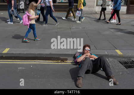 Les passants regarder vers le bas sur une jeune militante se reposant avec sa tête sur un trottoir de l'Oxford Circus 4 journée de manifestations des militants de l'environnement changement climatique groupe de pression avec l'extinction de la rébellion, le 18 avril 2019, à Londres, en Angleterre. Banque D'Images