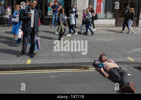 Les passants regarder vers le bas sur une jeune militante se reposant avec sa tête sur un trottoir de l'Oxford Circus 4 journée de manifestations des militants de l'environnement changement climatique groupe de pression avec l'extinction de la rébellion, le 18 avril 2019, à Londres, en Angleterre. Banque D'Images