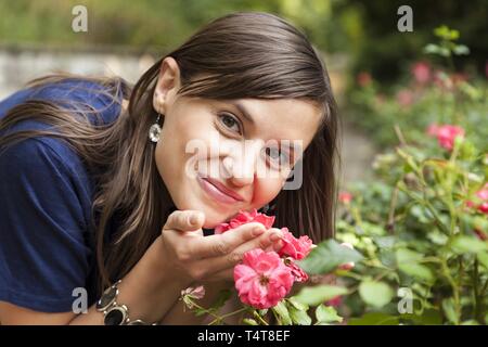 Young woman smelling roses, Allemagne Banque D'Images