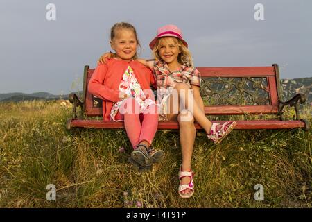 Les enfants (5, 6) assis sur un banc, coucher de soleil, Afionas, Corfou, Grèce, Europe Banque D'Images