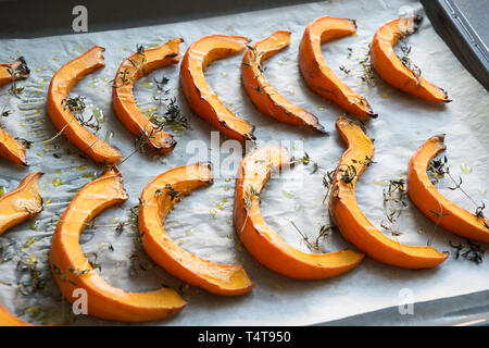 Petites Tranches de rôti au thym de citrouille, l'huile d'olive et de sel sur du papier sulfurisé et lèchefrite. Vegan délicieux en-cas. Patern alimentaire. Banque D'Images