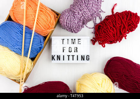 Flatlay pastel multicolore d'écheveaux de fil à tricoter et des aiguilles à tricoter avec lettrage - de temps pour le tricot Banque D'Images