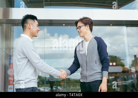 Portrait of mid adult réussie partners shaking hands, looking at camera et souriant. Banque D'Images