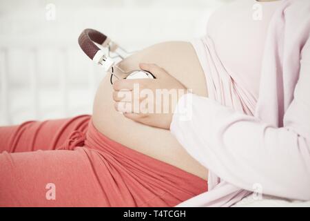 Pregnant woman holding casque dans le ventre Banque D'Images