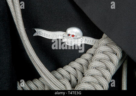 La COLLECTION JOHN PEPERA, une soirée Robe Veste de SS-Sturmbannführer Dr Lüdcke sur mesure, de laine noire doeskin double-breasted taille Veste avec col ouvert et Revers en soie noire, argent/aluminium garniture cordon sur le col et poignets, argent/aluminium boutons avec les runes et couronne en relief levé. Collier laine noir tabs bordé d'argent/aluminium, cordon lisse sur le côté droit, rang 4 pips sur la gauche. Argent/aluminium interwoven épaulettes cordon noir sur fond rouge de la laine, de la laine et soie gros-grain, bordés de brassard cordon argent/aluminium, un vieux Fighter's chevro, Editorial-Use-seulement Banque D'Images