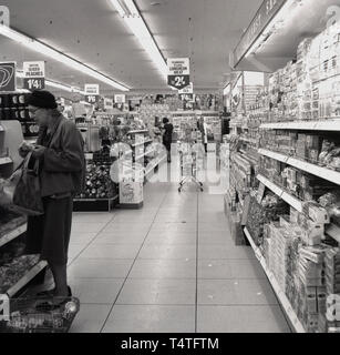 Années 1960, historique, les femmes à l'intérieur de l'acheteur une allée dans une nouvelle 'Fine Fare' supermarché, Londres, Angleterre. Tarif fine a commencé comme dépanneurs dans les années 1950, puis elle est devenue une chaîne de supermarchés dans la décennie suivante, la vente d'une variété de produits, y compris les pêches et silced le pain de viande de porc. Banque D'Images