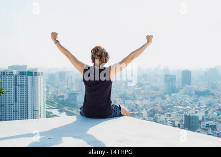 Homme assis sur le toit noir et show de main avec fond de ciel bleu et de soleil,la lutte contre l'homme sur le toit Banque D'Images