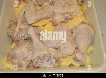 Morceaux de poulet cru et pommes de terre en tranches, mariné avec de la mayonnaise et disposés dans un plat de cuisson en céramique. Maison de vacances cuisine nourriture pour Noël, Pâques, Banque D'Images