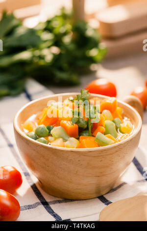 Louche de jeunes légumes fraîchement récoltés à la vapeur y compris les carottes, en Coupe ondulée, de pois et de pommes de terre pour un accompagnement sain pour le dîner Banque D'Images