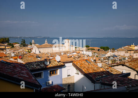 Vue sur les toits rouges de petite ville sous ciel magnifique au coucher du soleil en automne en Garda, Italie. Toits de maisons traditionnelles italiennes. Banque D'Images