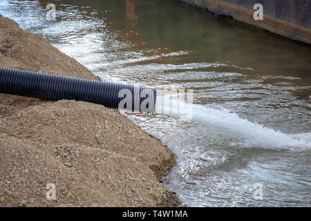 Travaillant à haute pression de la pompe de la rivière. Jet de l'eau de la pompe à eau. Système de protection contre les inondations, l'eau du tube, à une rivière. Banque D'Images