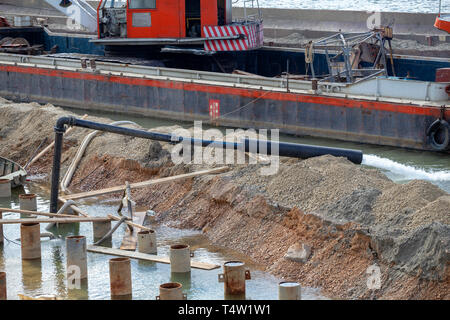 Travaillant à haute pression de la pompe de la rivière. Jet de l'eau de la pompe à eau. Système de protection contre les inondations, l'eau du tube, à une rivière. Banque D'Images