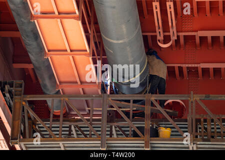 Les travailleurs soudeur soudure tuyaux sous pont métallique. Banque D'Images