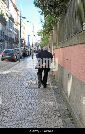 Personnes âgées représentant senior flaneur portant un costume gris se promener le long de la Rua da Cedofeita à quartier à Porto Portugal KATHY DEWITT Banque D'Images