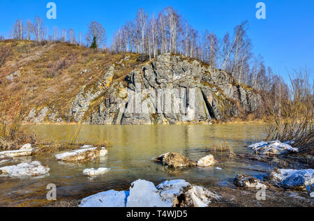 Début du printemps paysage de rivière avec rocky banques et forêt de bouleaux en haut de falaise, avec la fonte de la Neige et ciel bleu clair - Beauté de printemps si Banque D'Images