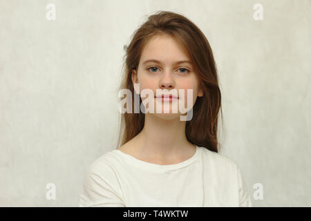 Brune aux yeux bleus jeune fille timide en t-shirt. Modèle de studio photo. Banque D'Images