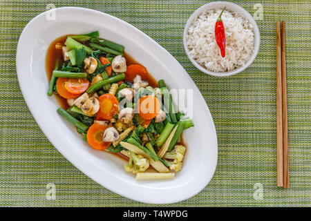 Thai légumes sautées et champignons dans la sauce d'huître, servi avec du riz. Baguettes en bois sur le côté. Vue d'en haut. Banque D'Images