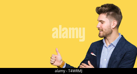 Beau Jeune homme cherche à faire sourire fier, geste Thumbs up sur le côté Banque D'Images
