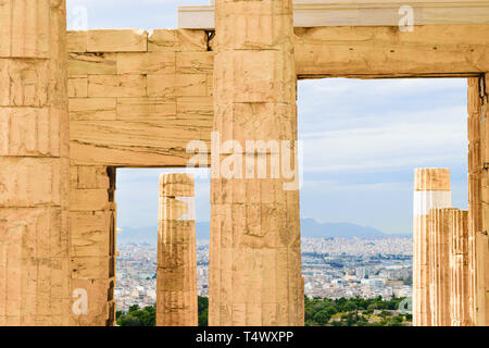 Montagnes et vue sur la ville d'Athènes entre les piliers de portes monumentales des Propylées de l'Acropole dans nuageux et pluvieux jour en Grèce Banque D'Images