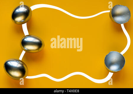 Les oeufs et les coquilles d'argent sur fond de couleur lumineux Banque D'Images
