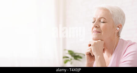 Calme senior woman meditating, écouter de la musique classique Banque D'Images