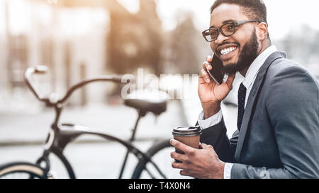 Smiling businessman talking on phone sitting outdoors Banque D'Images
